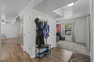 Hall featuring a textured ceiling, wood finished floors, and crown molding