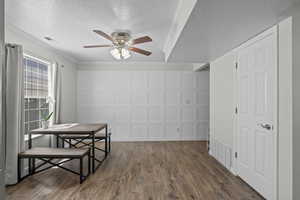 Dining area with a ceiling fan, a textured ceiling, dark wood-type flooring, and ornamental molding