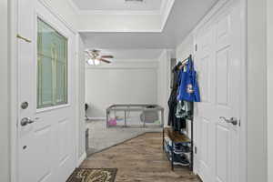 Entryway with wood finished floors, ornamental molding, and ceiling fan