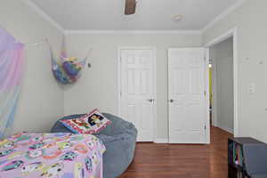 Bedroom with crown molding, wood finished floors, and ceiling fan