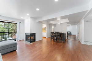 Living room with wood finished floors, recessed lighting, and a multi sided fireplace