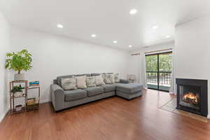 Living room with wood finished floors, a multi sided fireplace, and recessed lighting
