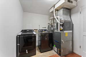 Washroom with independent washer and dryer and light wood-style floors