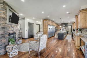 Living area with wood finished floors, recessed lighting, a stone fireplace, and stairway