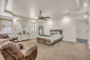 Carpeted bedroom featuring crown molding, a raised ceiling, ceiling fan, and recessed lighting