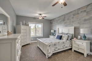 Bedroom with dark carpet, an accent wall, and ceiling fan
