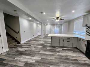 Kitchen with gray cabinetry, a peninsula, ceiling fan, recessed lighting, and dark wood-style floors