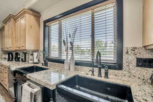 Kitchen featuring light brown cabinetry, tasteful backsplash, healthy amount of natural light, and light stone countertops