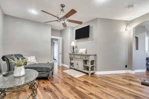 Living area featuring arched walkways, ceiling fan, and wood finished floors