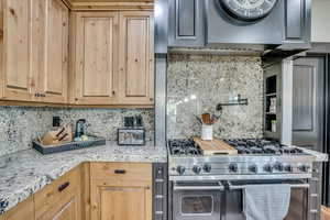 Kitchen featuring double oven range, tasteful backsplash, and range hood