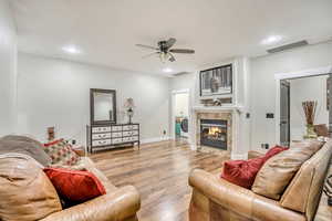 Living room featuring wood finished floors, attic access, washer / dryer, a fireplace, and ceiling fan