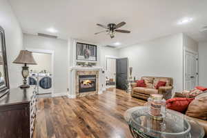 Living room featuring separate washer and dryer, attic access, wood finished floors, a ceiling fan, and a fireplace