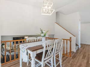 Dining space featuring wood finished floors, stairs, a chandelier, and lofted ceiling