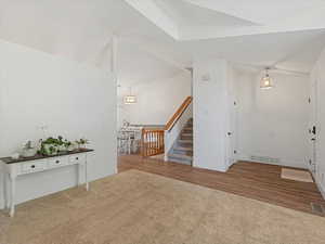 Entrance foyer featuring carpet floors, stairway, and wood finished floors