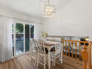 Dining area with wood finished floors, a chandelier, and vaulted ceiling