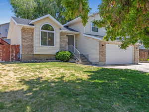 Tri-level home featuring driveway, brick siding, and an attached garage