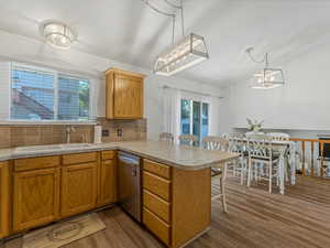 Kitchen featuring stainless steel dishwasher, a peninsula, dark wood-style flooring, a breakfast bar area, and tasteful backsplash
