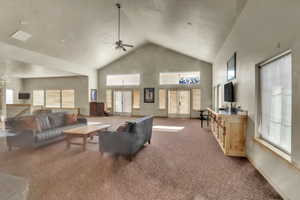 Living room featuring high vaulted ceiling, ceiling fan, and light carpet