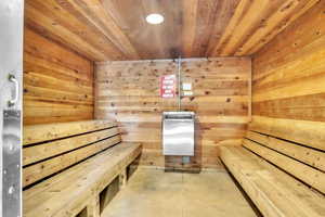 Relaxing sauna / steam room with wood ceiling, wooden walls, and concrete flooring