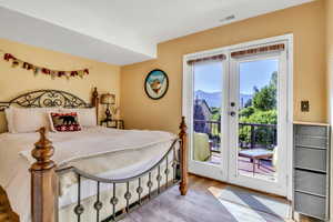 Bedroom with access to exterior, wood finished floors, and french doors