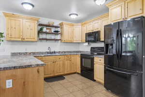 Kitchen featuring black appliances, open shelves, light brown cabinets, dark countertops, and a textured ceiling