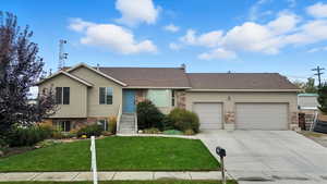 View of front of property featuring stone siding, roof with shingles, a front yard, a garage, and concrete driveway