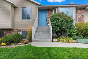 Property entrance featuring a lawn, stone siding, and a chimney