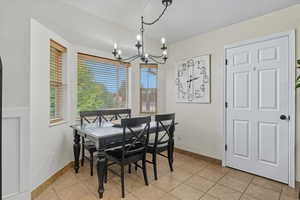Dining space with plenty of natural light, light tile patterned flooring, and a chandelier