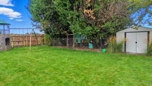 Fenced backyard featuring a playground and a shed