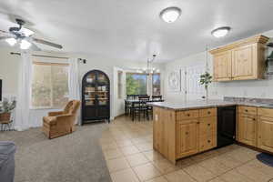 Kitchen featuring a textured ceiling, light tile patterned floors, a peninsula, light colored carpet, and light brown cabinetry