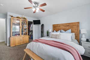 Carpeted bedroom with a spacious closet and a ceiling fan