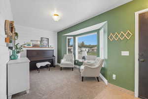 Living area featuring light colored carpet, light tile patterned flooring, and wood walls