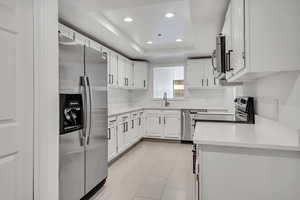 Kitchen with stainless steel appliances, recessed lighting, quartz countertops & white cabinetry