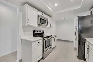 Kitchen with stainless steel appliances, recessed lighting, quartz countertops & white cabinetry