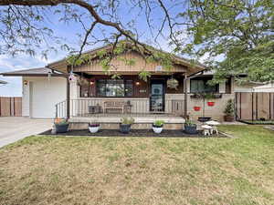 View of front facade with covered porch, a garage, concrete driveway, and brick siding