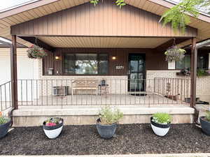 View of exterior entry featuring covered porch and brick siding