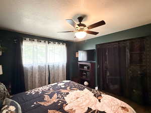 Bedroom with a textured ceiling, a ceiling fan, and wood finished floors