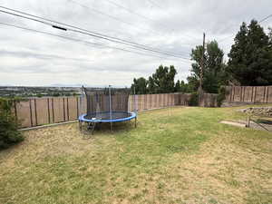 Fenced backyard featuring a trampoline