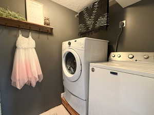 Washroom featuring independent washer and dryer and a textured ceiling
