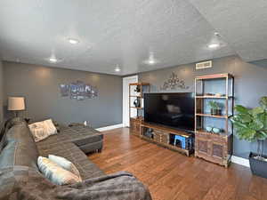Living room with a textured ceiling, wood finished floors, and recessed lighting