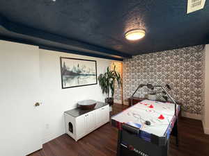 Playroom featuring wallpapered walls, dark wood-type flooring, and an accent wall