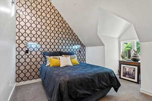 Carpeted bedroom with lofted ceiling and an accent wall