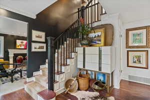 Stairs featuring ornamental molding and wood finished floors