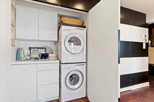 Washroom featuring stacked washer / drying machine and dark wood-type flooring