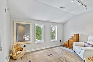 Sitting room with rail lighting, lofted ceiling, carpet floors, and stairs