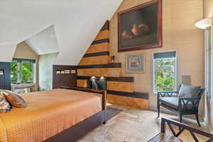 Bedroom featuring stone finish flooring and vaulted ceiling
