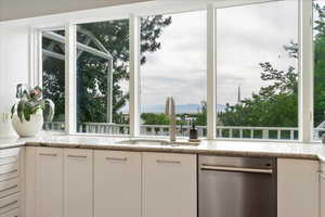 Kitchen featuring dishwasher, white cabinets, light stone countertops, and a mountain view