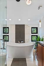 Bathroom featuring a freestanding tub, recessed lighting, vanity, a shower, and tile walls