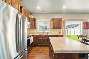 Kitchen with appliances with stainless steel finishes, dark wood finished floors, backsplash, light countertops, and recessed lighting