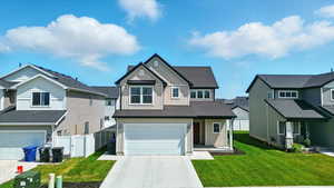 Craftsman house with board and batten siding, a garage, concrete driveway, and a residential view